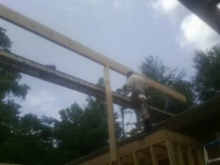 Carpenter setting a ridge beam over a new addition frame — Ice Dam Removal by Roofing Brothers in Lansing
